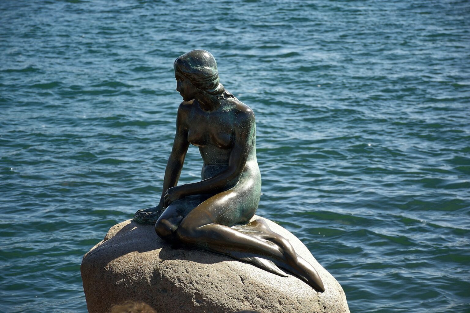 a statue of a mermaid sitting on a rock